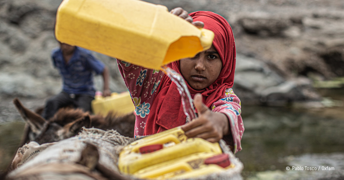 jeune femme yéménite transvasant de l'eau dans un bidon